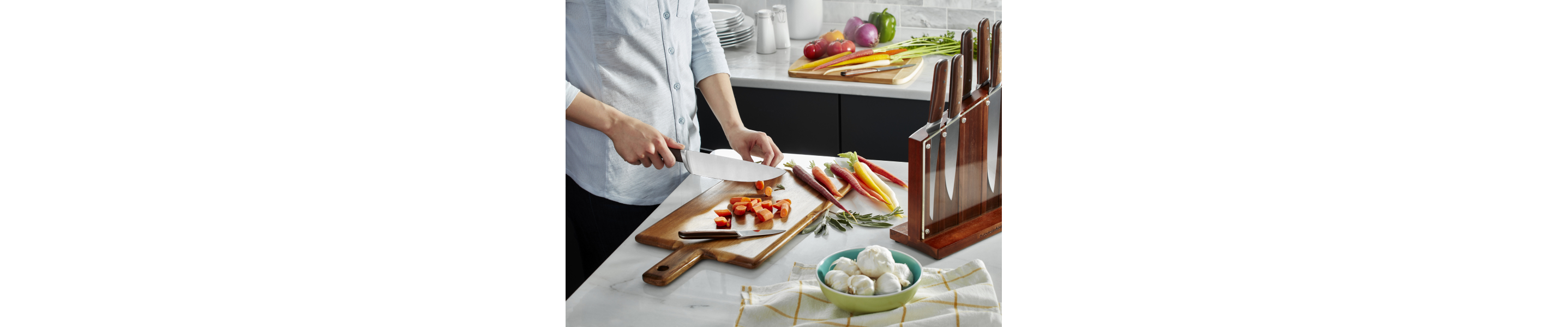 A man chopping carrots on a cutting board in a modern kitchen.