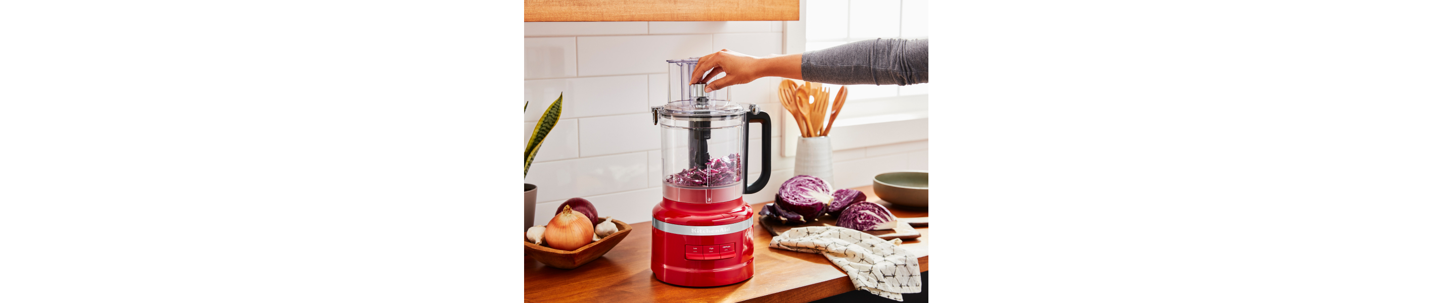 A woman chopping purple cabbage in a KitchenAid® food processor.