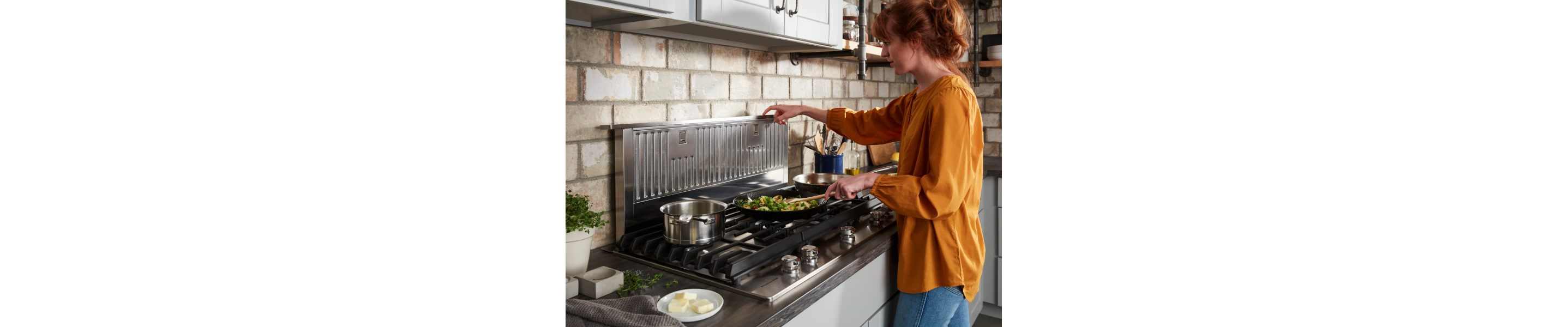 A woman stir frying vegetables on a KitchenAid® stovetop.