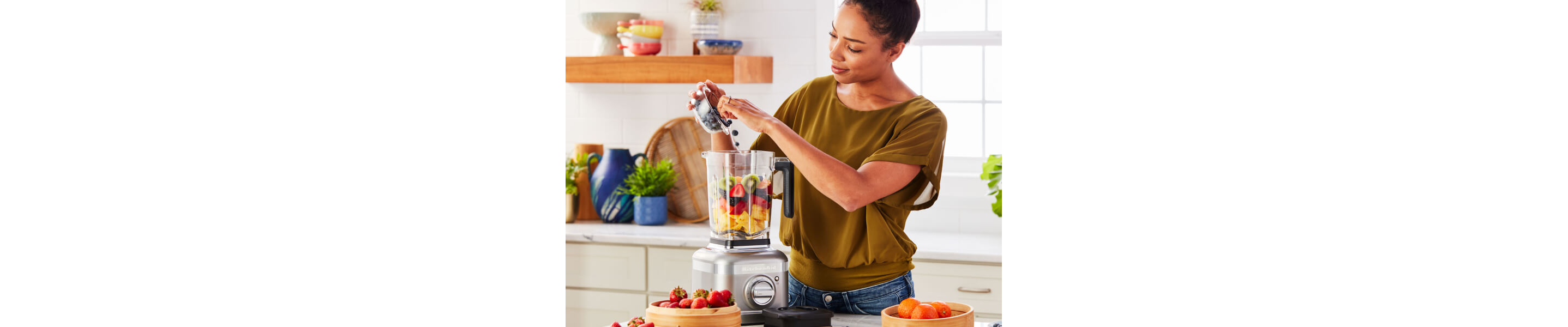 Person adding fresh fruit to a KitchenAid® blender