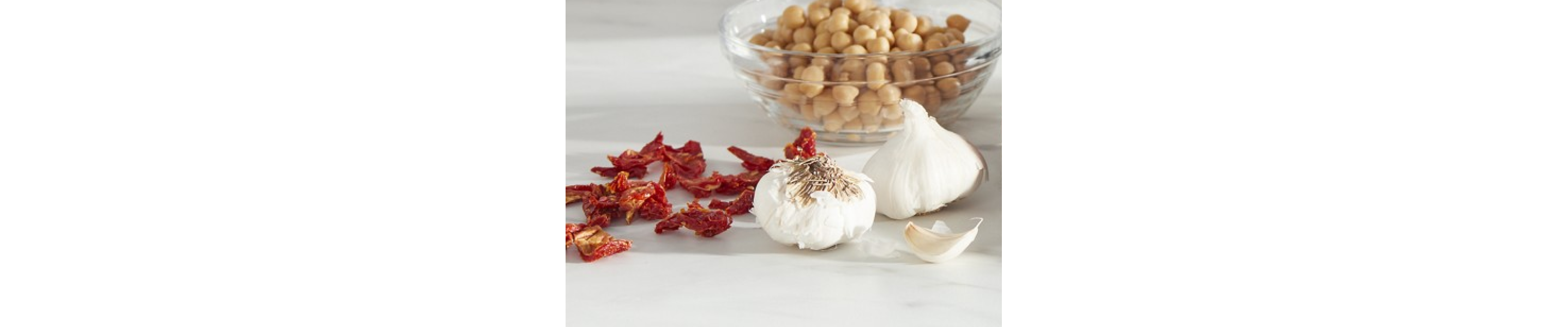 Chickpeas in bowl next to whole garlic and dried herbs