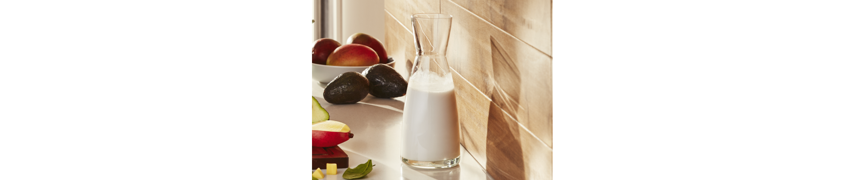Small pitcher of milk on counter with fresh ingredients