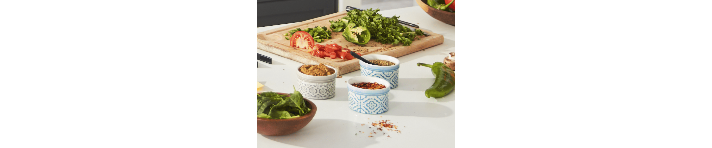 Chopped tomato and peppers on cutting board next to bowls of spices