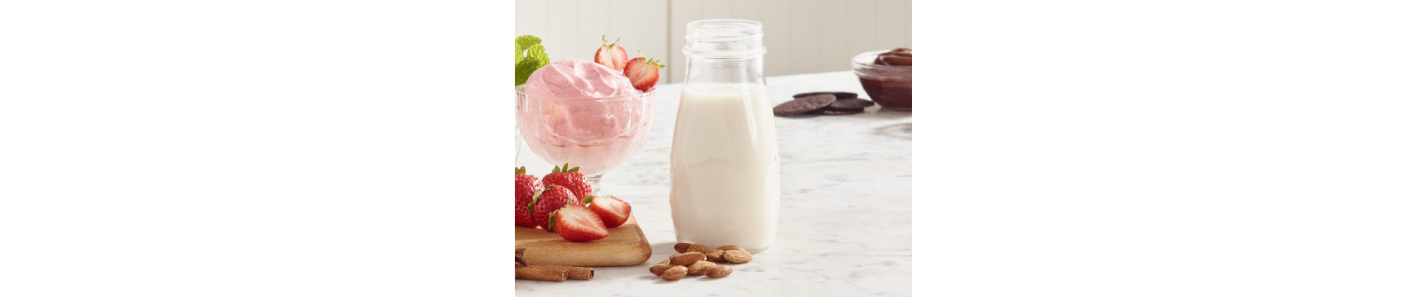 Strawberry ice cream next to a glass of milk.