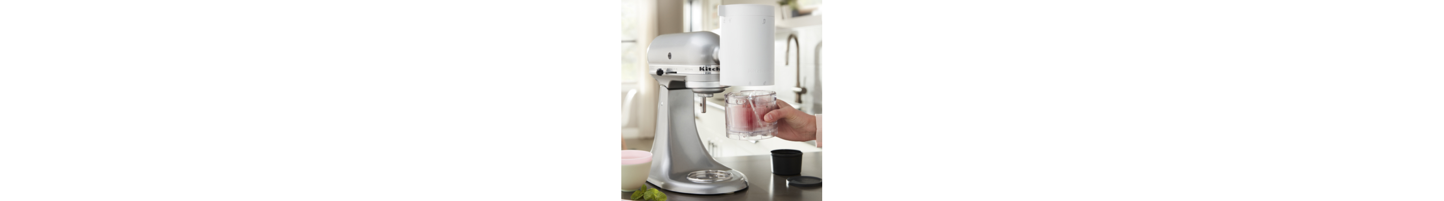 Hand holding a glass cup under a KitchenAid® Stand Mixer with Shave Ice Attachment