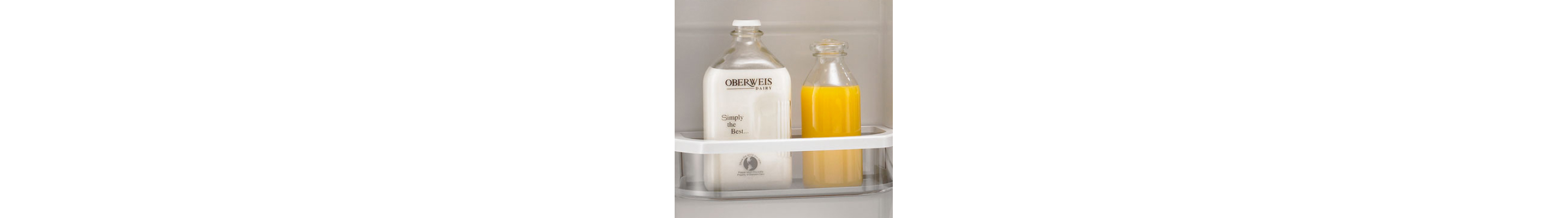 Glass jug of orange juice next to a glass jug of milk