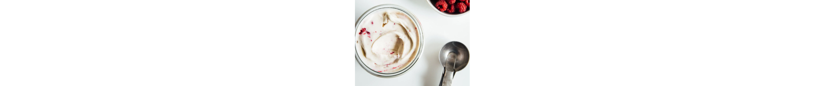 A dish of raspberry ripple nice cream next to an ice cream scooper