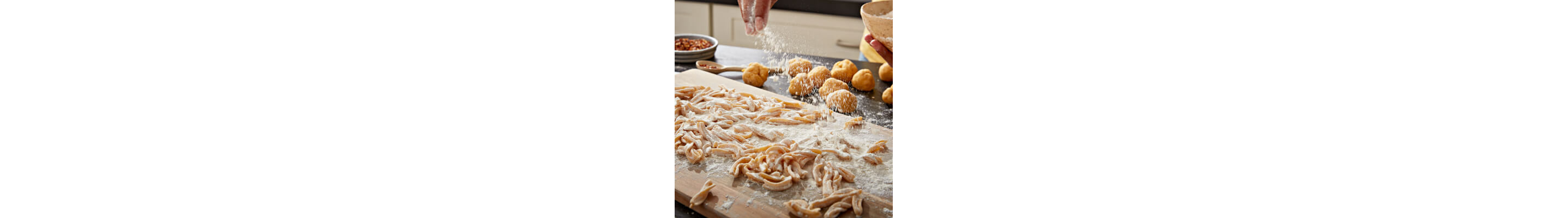Hand sprinkling flour on fresh pasta