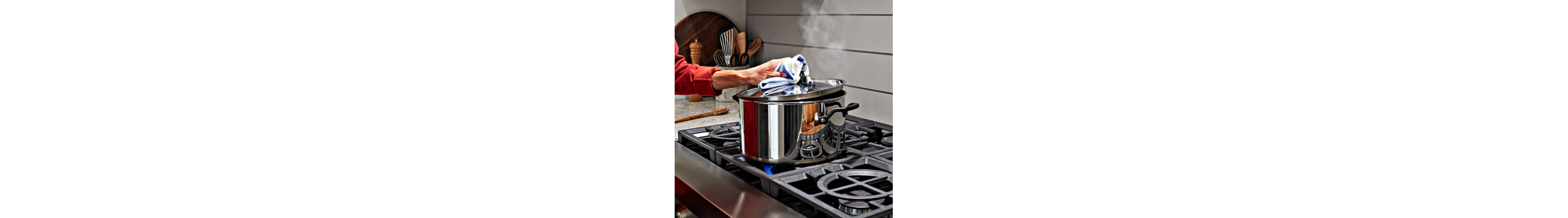 Hand lifting lid from large pot on cooktop