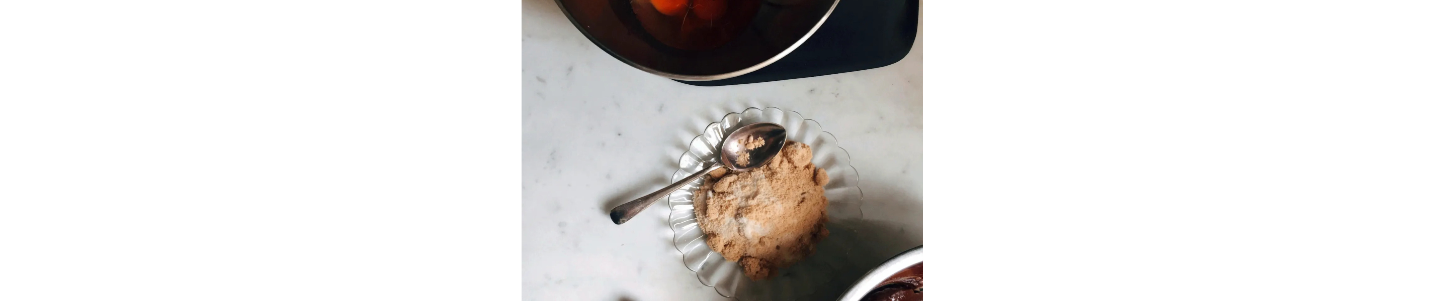 Dish of dry ingredients next to a bowl of cracked eggs