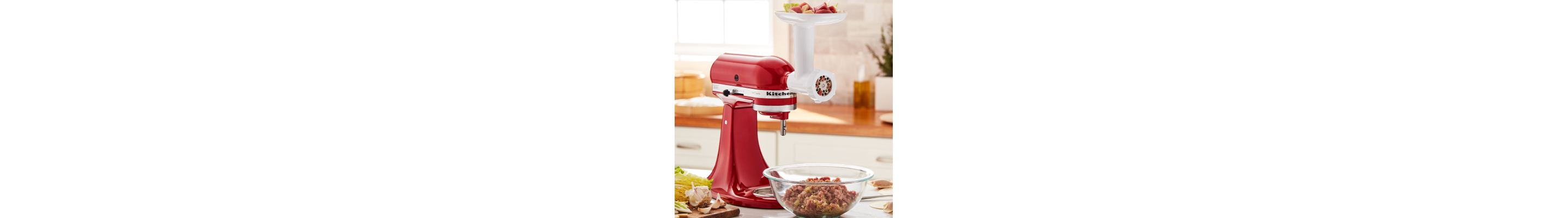KitchenAid® stand mixer with meat grinder attachment grinding meat into bowl