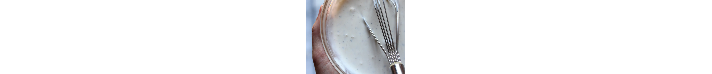 A whisk in a small bowl of tabouli dressing