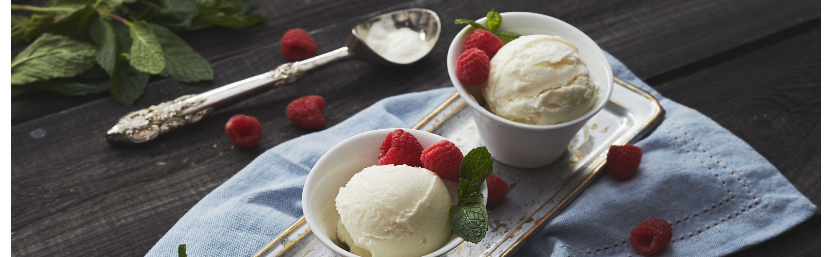 Individual bowls with scoops of vanilla ice cream and fresh raspberries on a table