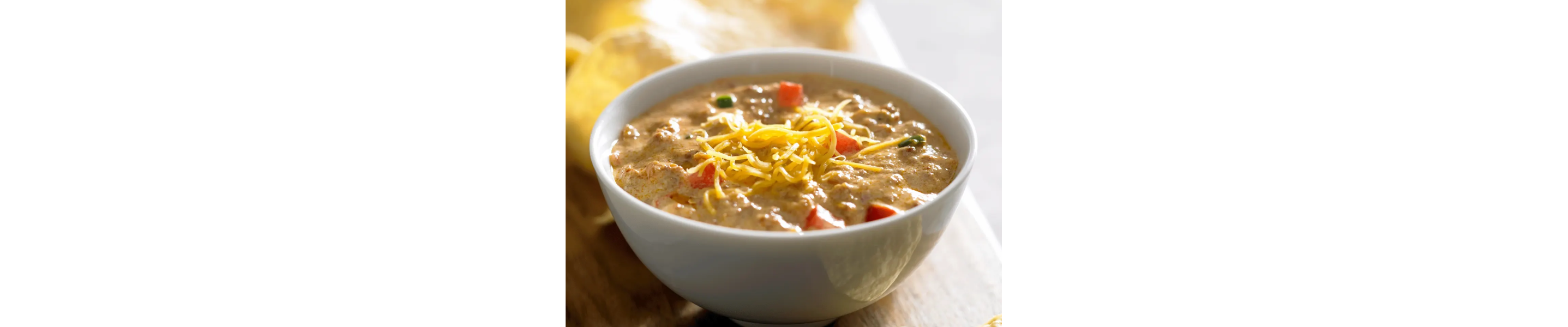 A bowl of homemade queso with shredded cheese sprinkled on top.