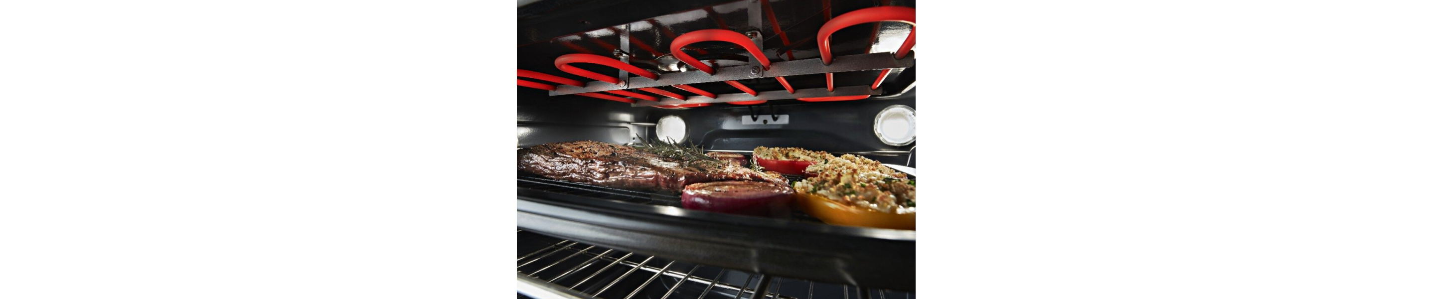 Close-up of roasting meat and vegetables beneath an oven heating element