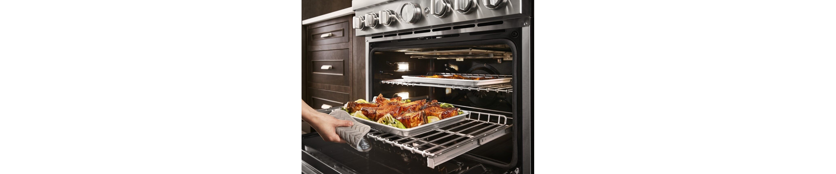 Person sliding out the bottom oven rack with a pan of food on top
