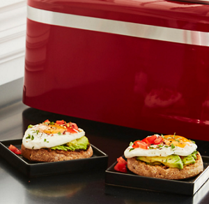 Two poached eggs on English muffins on a countertop next to various kitchen appliances