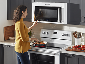 A person pushing a button on a microwave