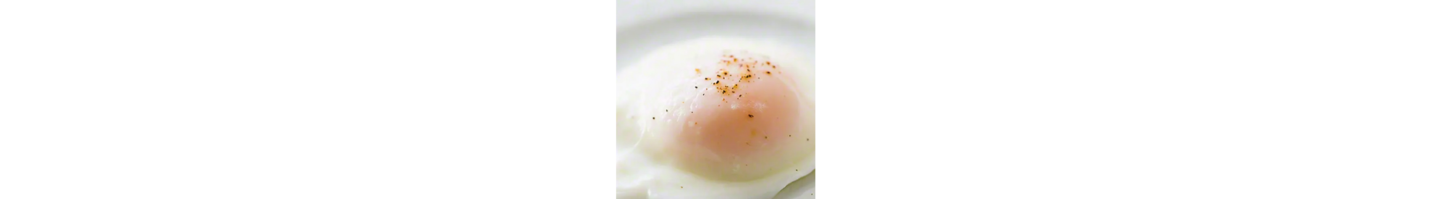 Close up of a poached egg topped with salt and pepper