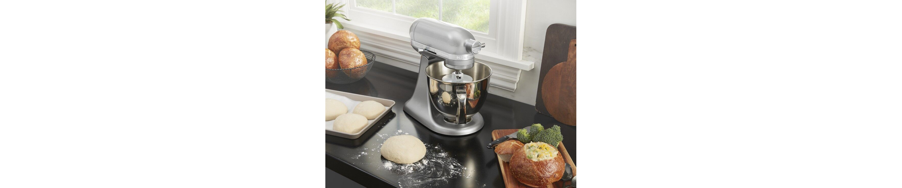 Shaped bread dough on countertop next to a silver KitchenAid® stand mixer