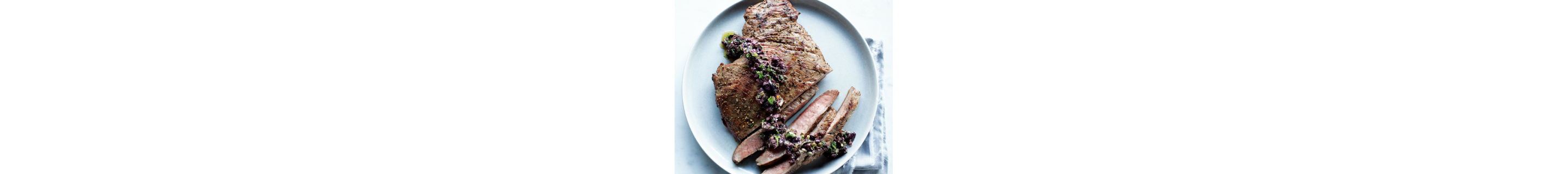 Seasoned steak half cut into slices garnished with vegetables