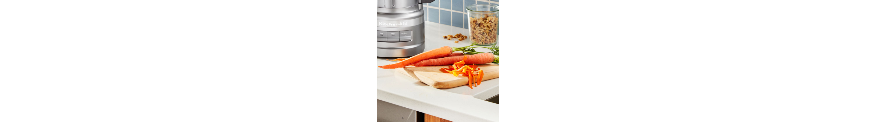 Carrots on a cutting board next to a KitchenAid® food processor