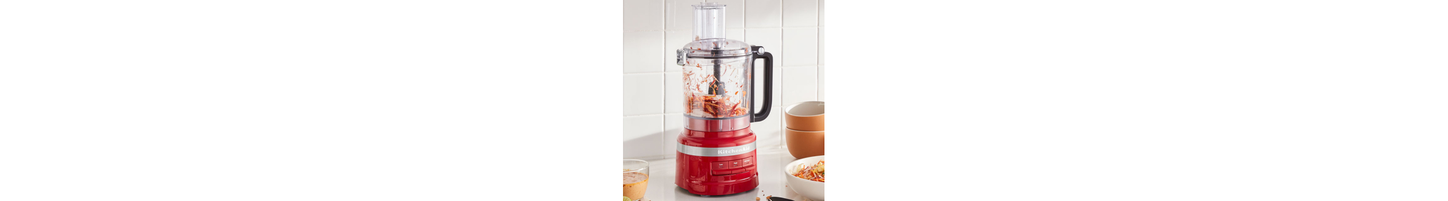 Carrots shredding inside a red KitchenAid® food processor
