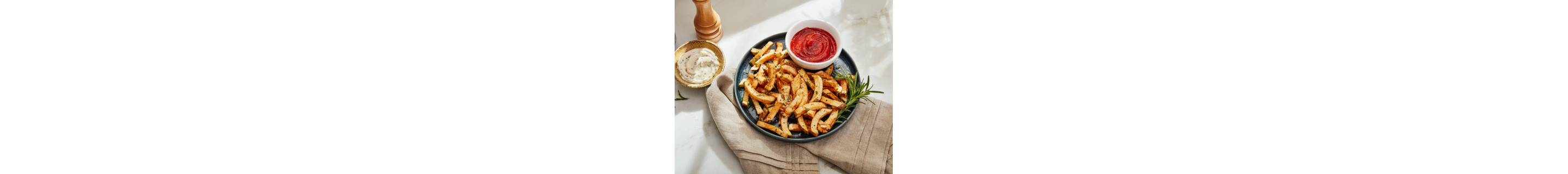 A plate of french fries with aioli and ketchup