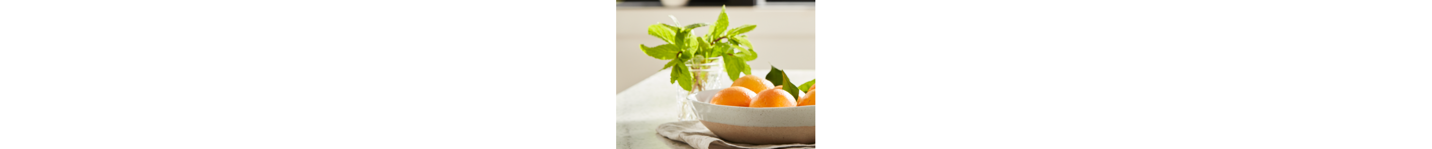 Bowl of oranges next to a jar of fresh herbs