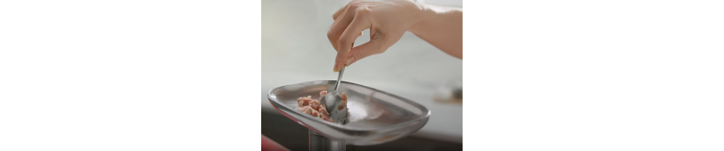 Person feeding meat into a grinder