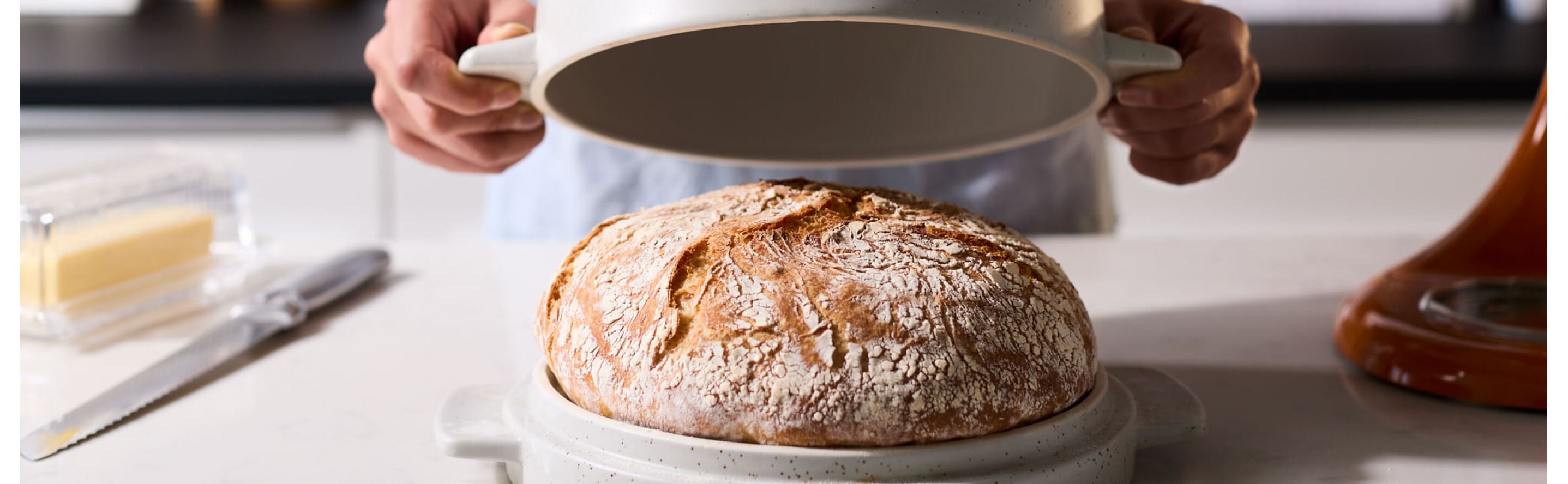 Bread in a bread bowl with person removing lid