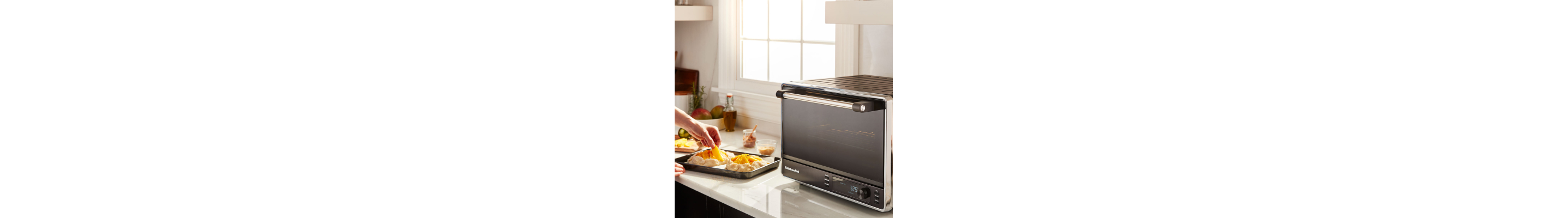 A person preheating a black KitchenAid® countertop oven to make pastries