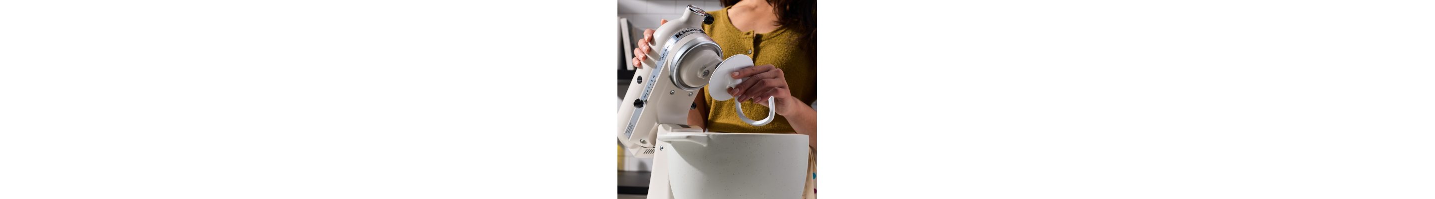 A person attaching a dough hook accessory to a stand mixer.