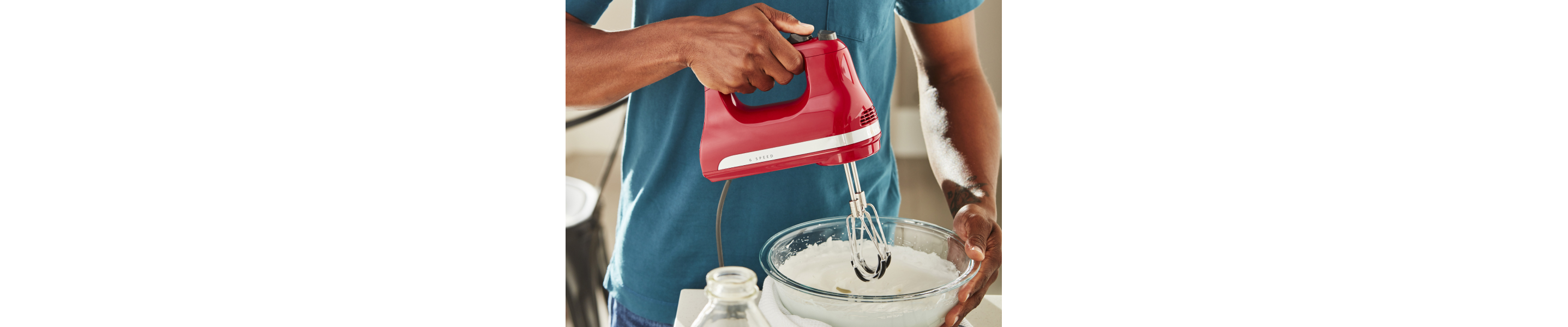 Person using KitchenAid® hand mixer over bowl of batter
