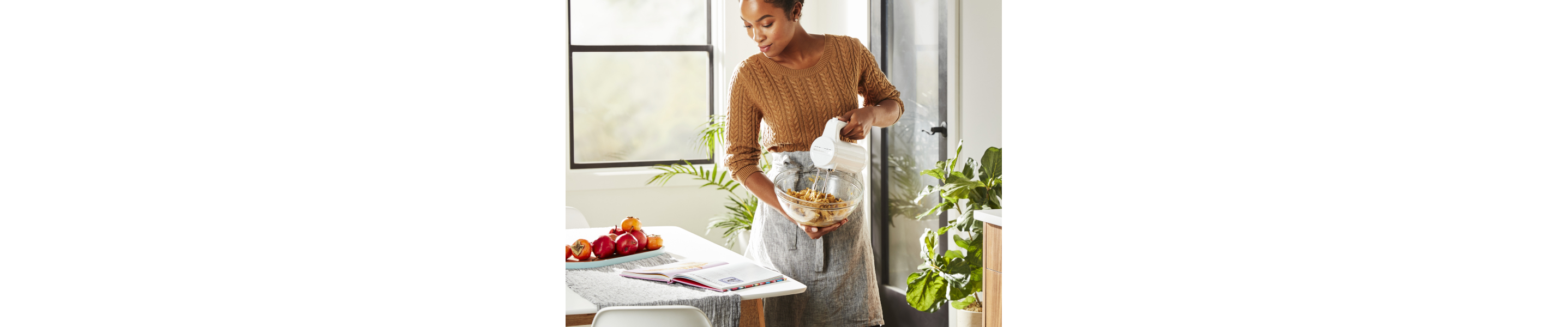 Person using KitchenAid® hand mixer and reading instructions