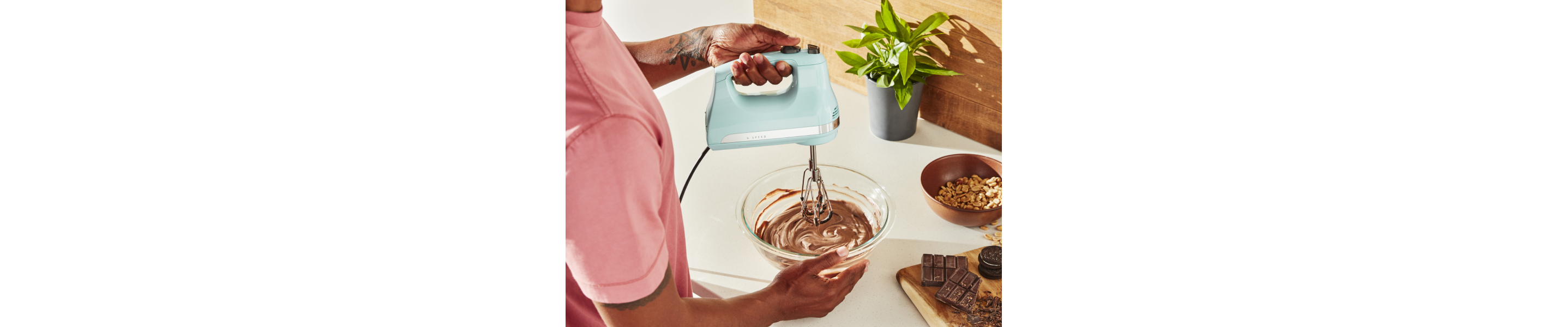 Person using KitchenAid® hand mixer over bowl of batter