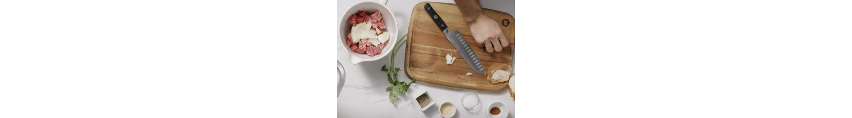 Person cutting onion to put into bowl with meat