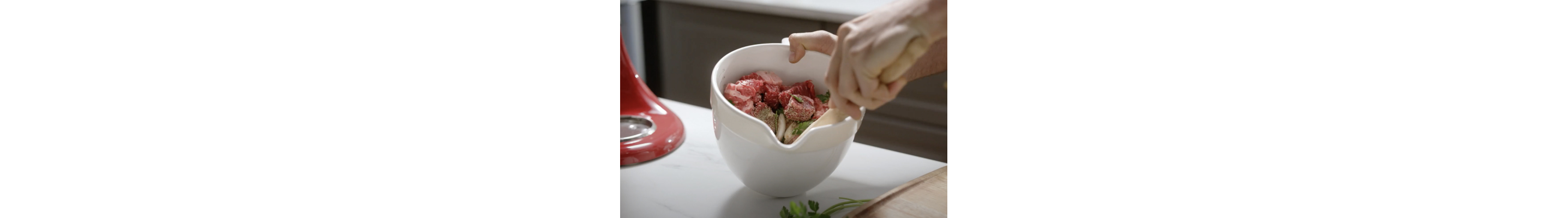 Cubed meat in a KitchenAid brand stand mixer bowl with seasoning