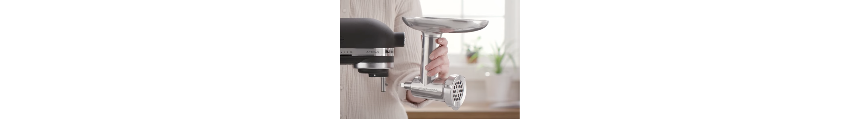 Person holding metal food grinder near stand mixer