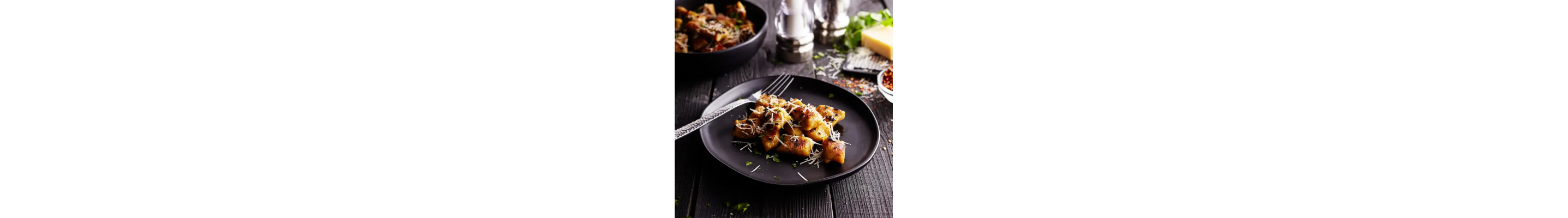 Fresh gnocchi on black plate with fork