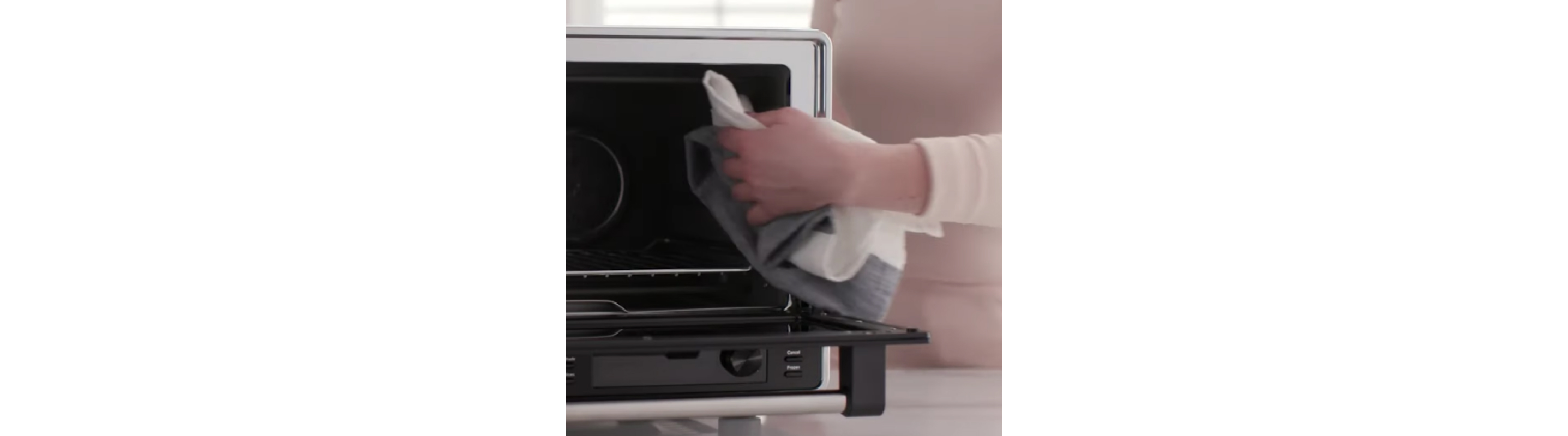 Person cleaning inside of air fryer with cloth. 