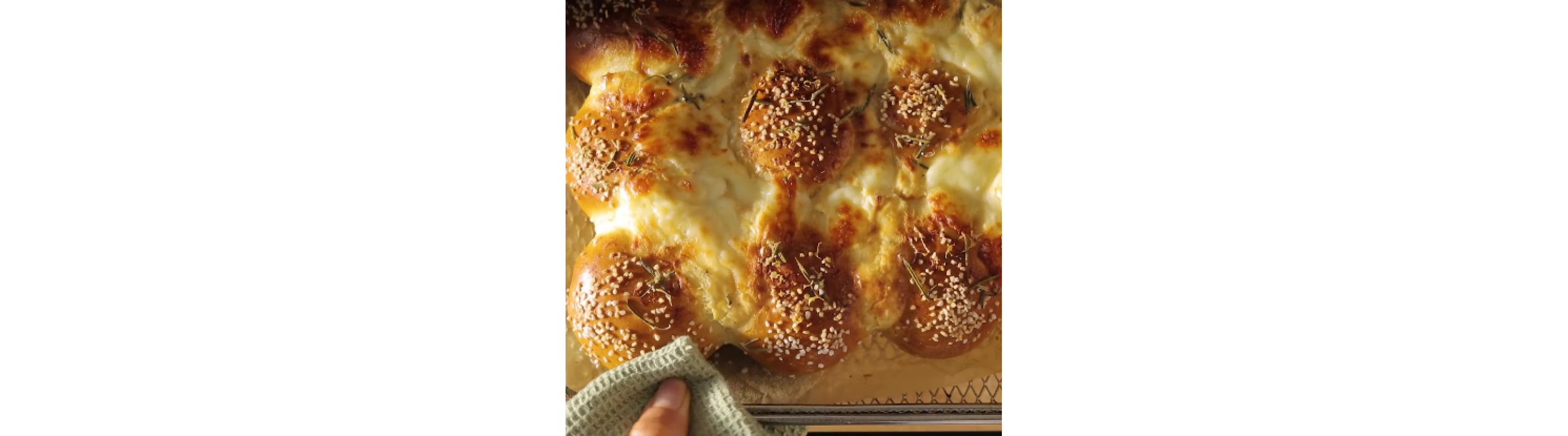 Close-up of hand removing air fryer basket full of bread.