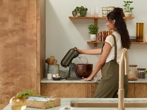 Person using a KitchenAid® Stand Mixer in a kitchen with natural wood tones
