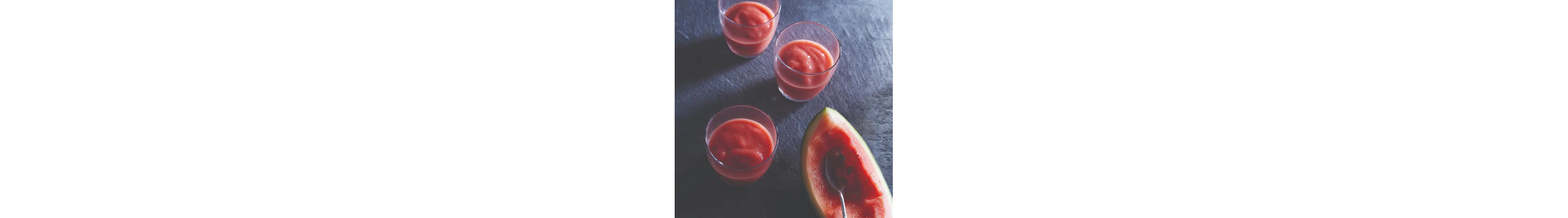 Three glasses of pink smoothie near a watermelon rind