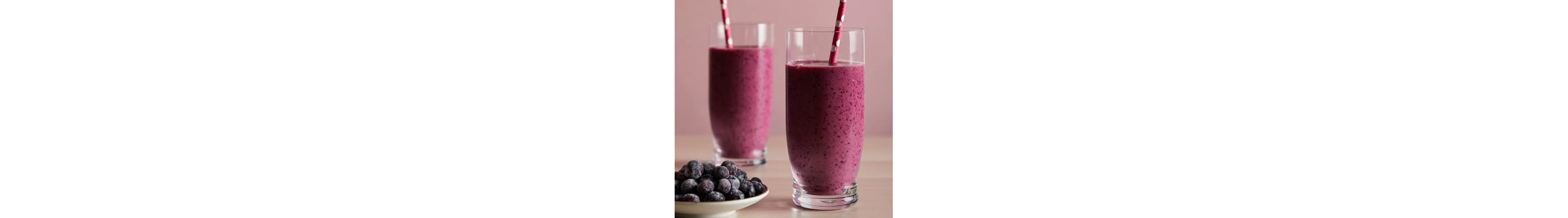 Two purple smoothies near a plate of frozen blueberries