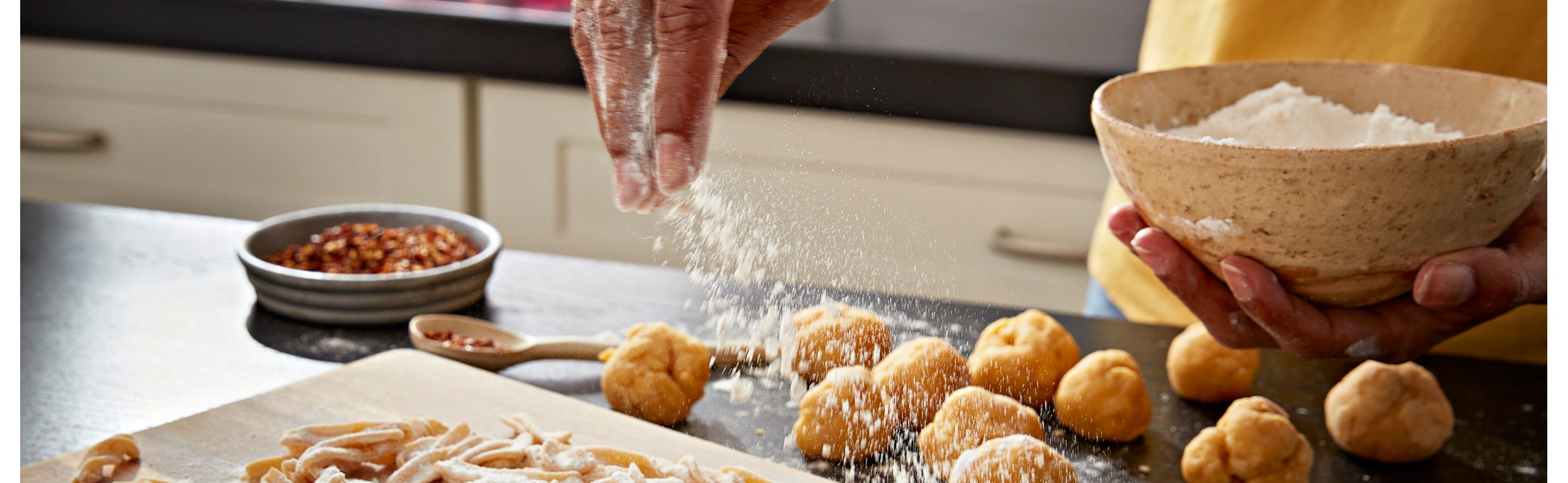A person sprinkling flour over dough