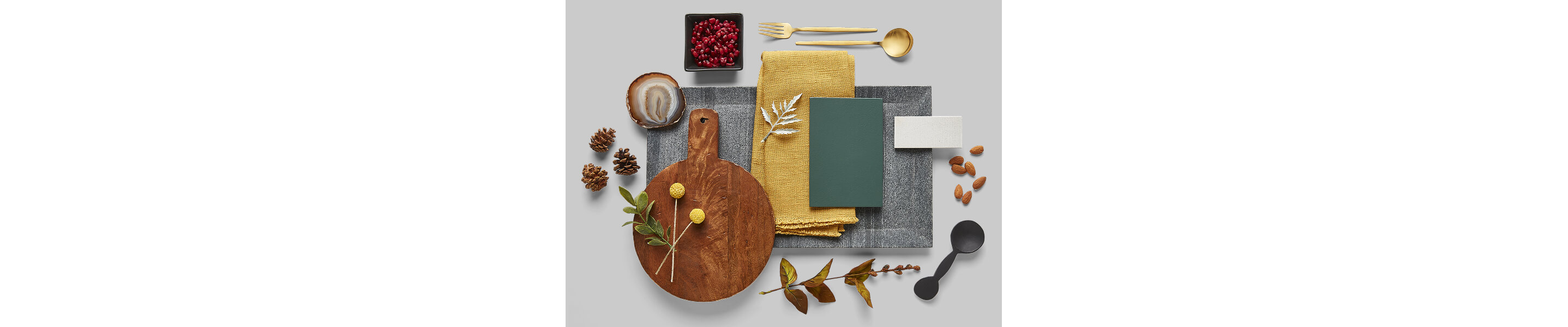 Accessories that look nice in a neutral-toned kitchen, including a wooden cutting board and mustard-colored cloth napkin