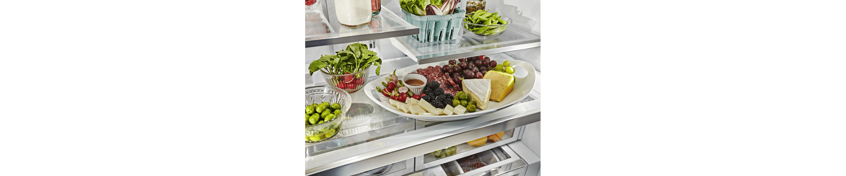 A slide-out tray with grapes, salami, olives, fruit and cheese.