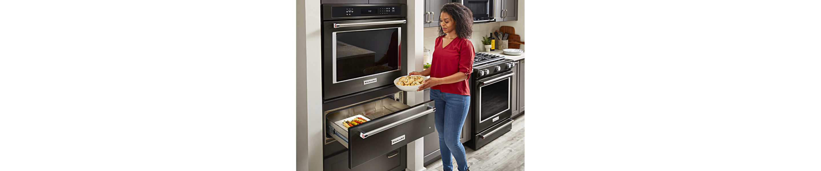Woman placing a bowl of dough in a KitchenAid® oven warming drawer