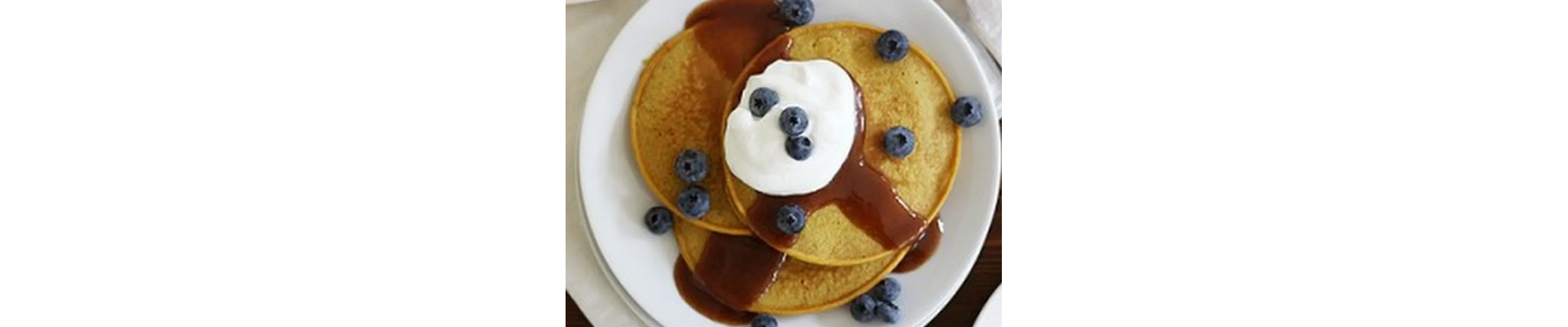 Plate of pumpkin pancakes with syrup, cool whip and blueberries on top